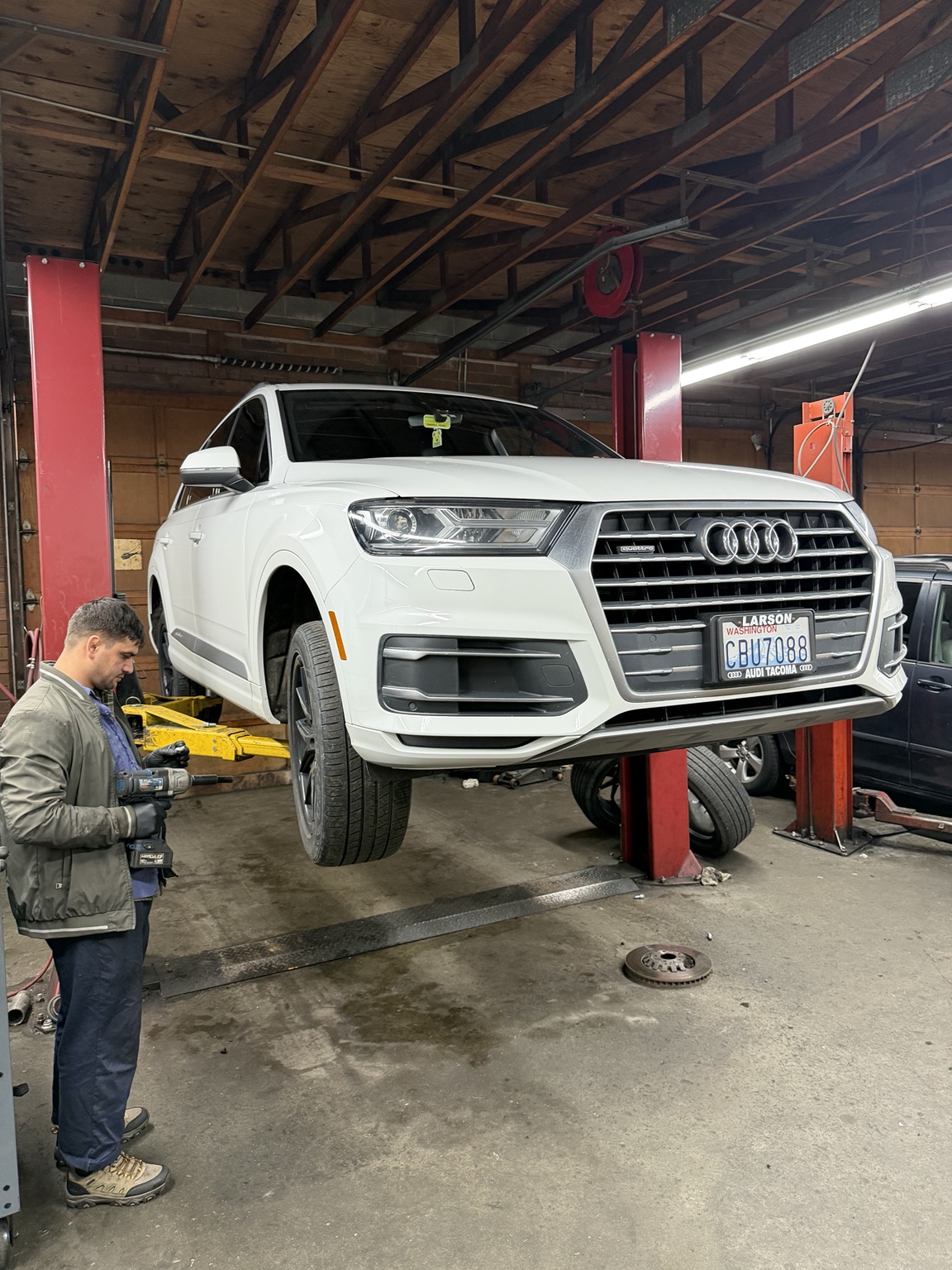 Technician servicing an Audi raised on a vehicle lift